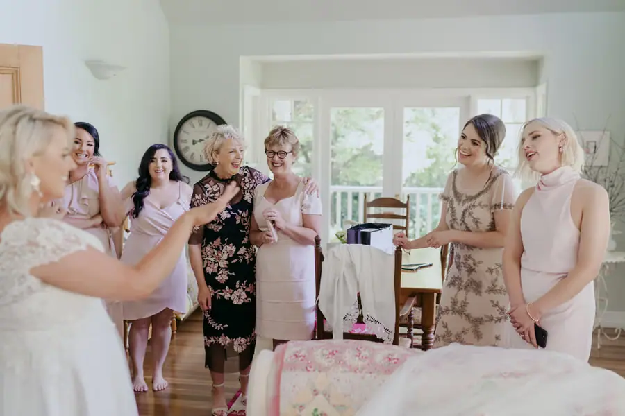Bride and friends smiling with champagne glasses in a bedroom