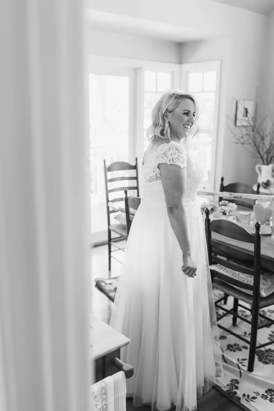 Black-and-white photograph of the bride standing in a bright doorway
