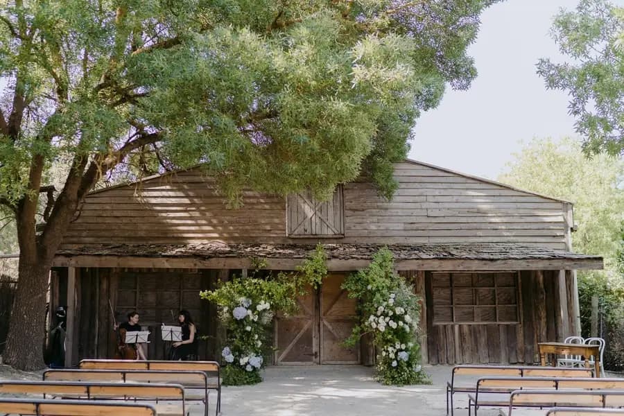 Rustic timber ceremony building with benches and climbing greenery