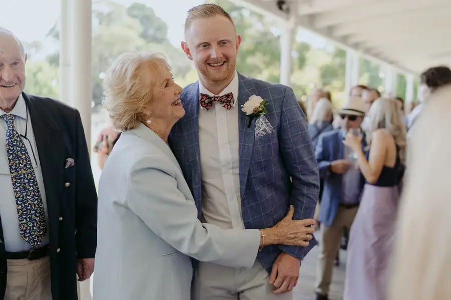 Groom embracing an older woman on a bright verandah