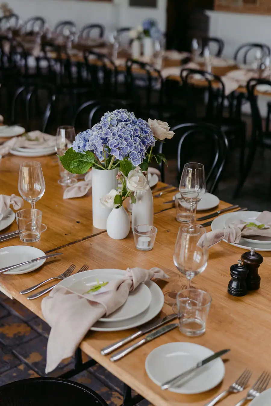 Blue flowers, glassware and pale napkins arranged on a wooden reception table