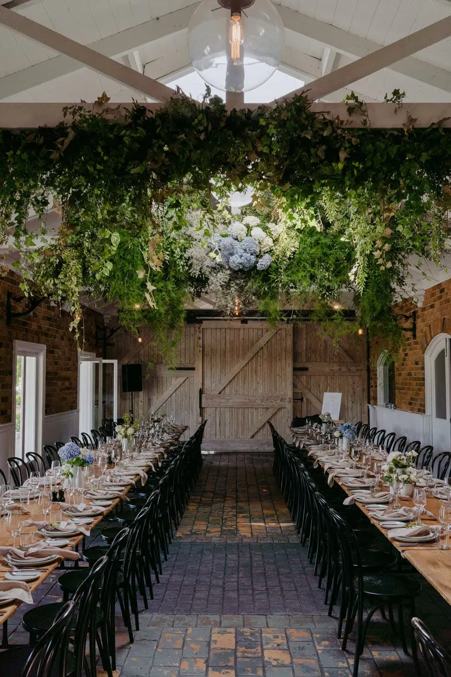 View between long reception tables toward a timber barn door