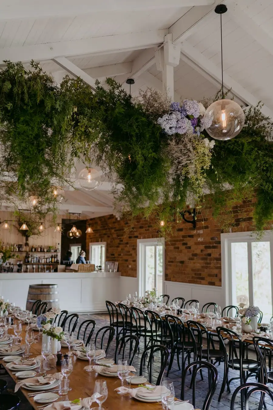 Decorated reception tables beneath hanging greenery and warm pendant lights