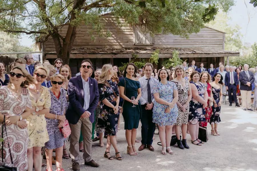 Standing wedding guests watching near the timber ceremony building