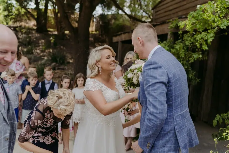 Bride smiling toward the groom as she arrives with her companions