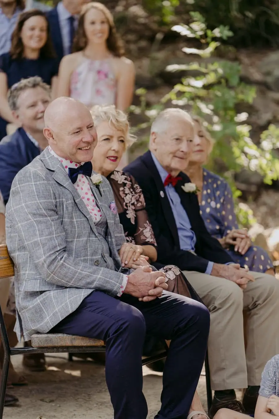 Seated guests laughing together on a wooden ceremony bench