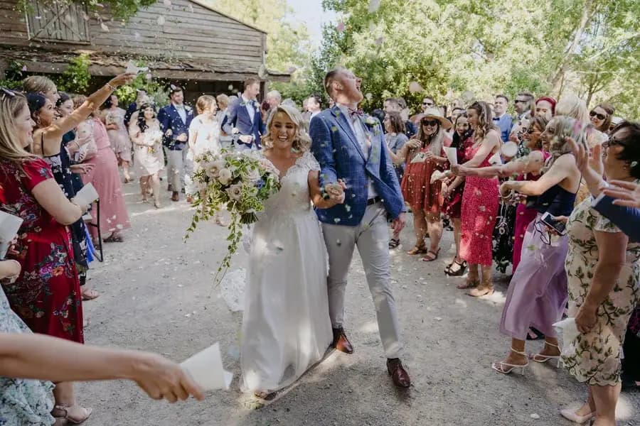 Bride and groom laughing beneath a shower of petals
