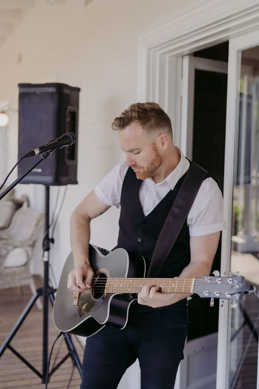 Musician playing an acoustic guitar on a verandah
