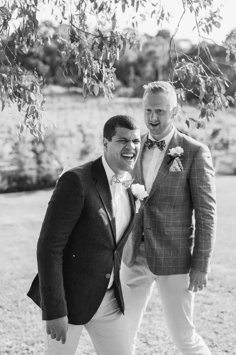 Black-and-white photograph of the groom posing closely with a smiling man