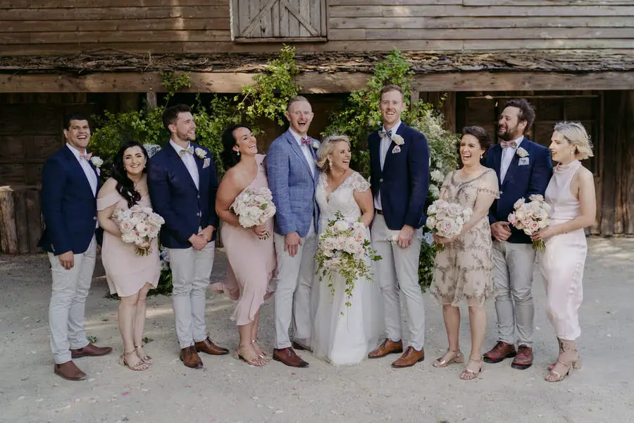 Wedding party laughing together outside a rustic timber building