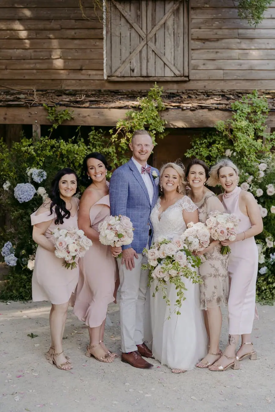 Bride and groom posing with four bridesmaids beside the ceremony building