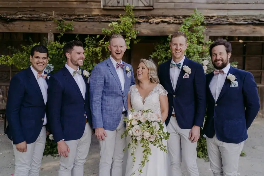 Bride and groom standing with four men in blue jackets