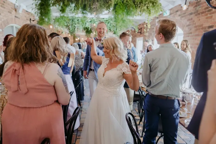 Bride and groom laughing as guests welcome them into the reception