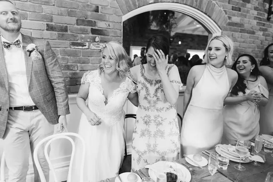 Black-and-white photograph of the couple and friends reacting during the reception