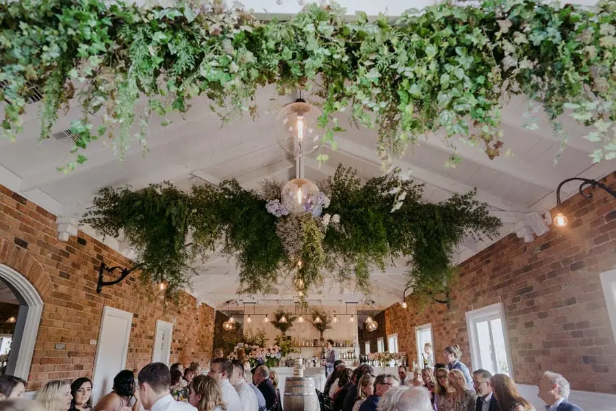 Reception guests seated beneath hanging flowers and greenery