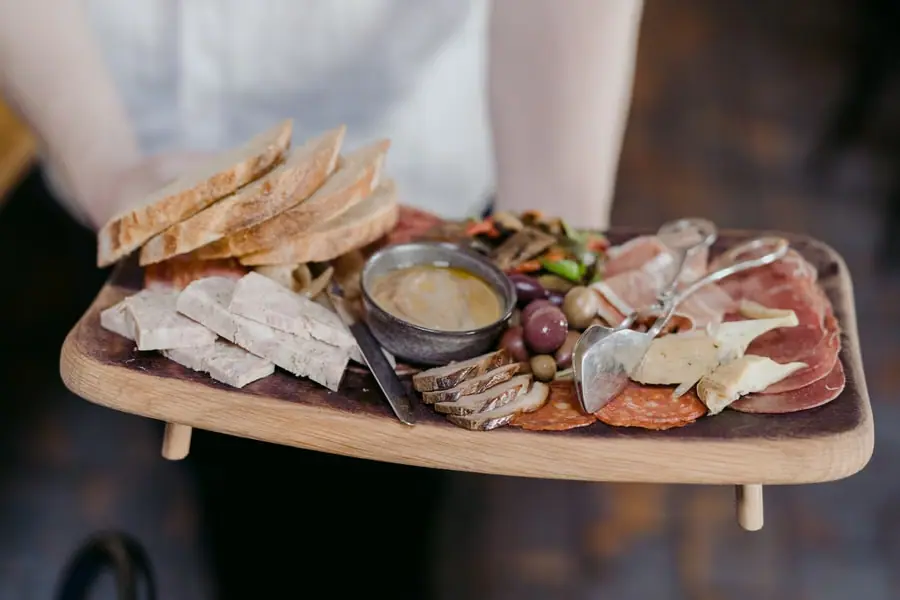 Wooden grazing board with bread, cheeses, cured meats and grapes