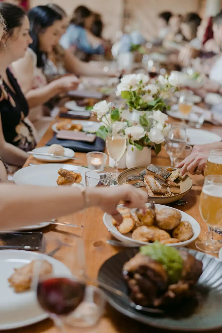 Guests sharing food along a flower-decorated reception table