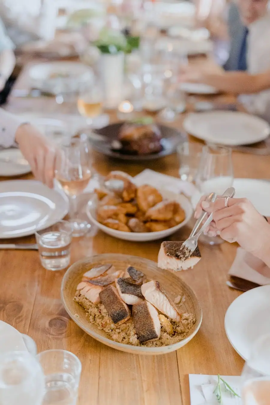 Shared platters and wine glasses arranged along a wooden dining table