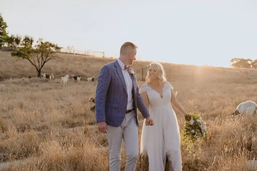 Bride and groom holding hands in golden evening sunlight