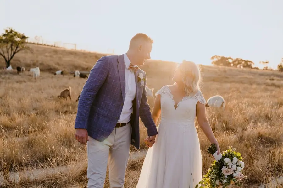 Bride and groom smiling at one another in a sunlit paddock