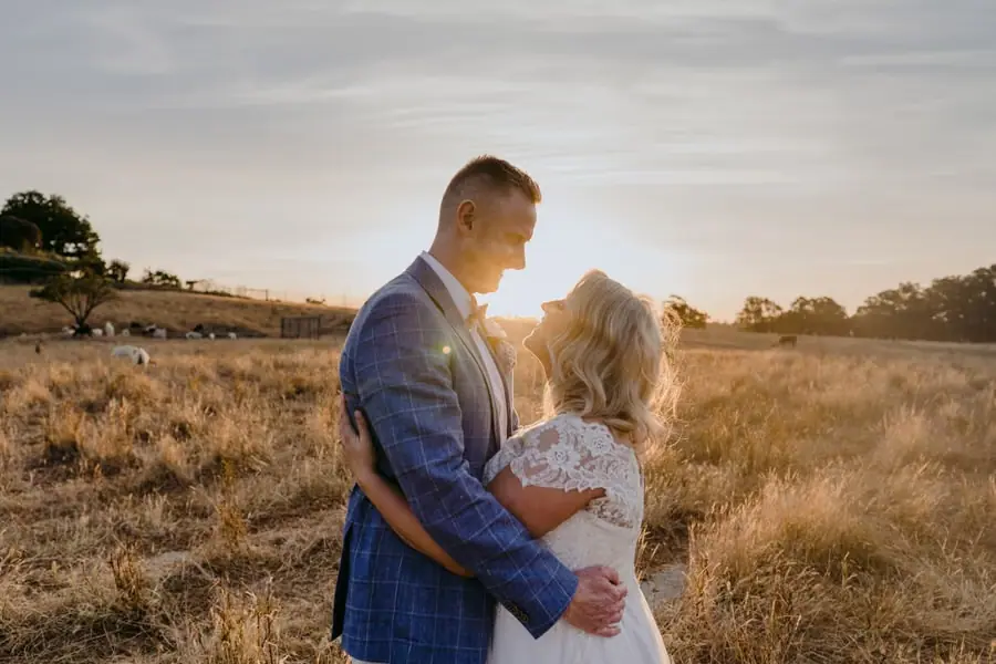 Bride and groom embracing as sunlight shines between their faces