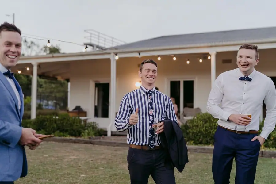 Men laughing with drinks outside the reception building