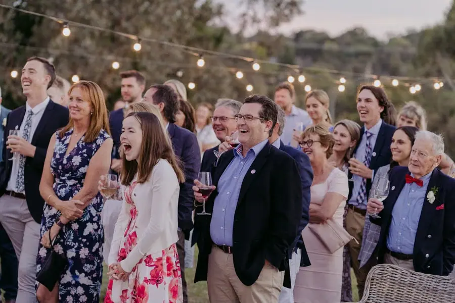 Wedding guests laughing beneath glowing outdoor lights