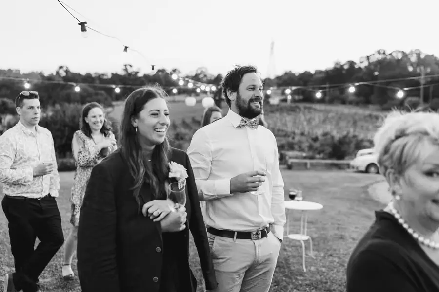 Black-and-white photograph of guests smiling beneath outdoor festoon lights