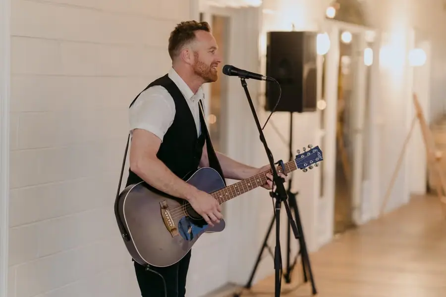 Musician singing into a microphone while playing an acoustic guitar