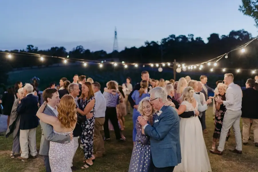 Wedding guests dancing together on the lawn in evening light