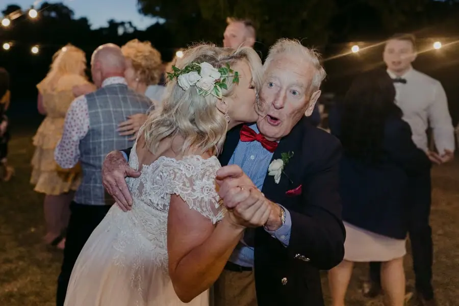 Bride dancing closely with an older man wearing a bow tie