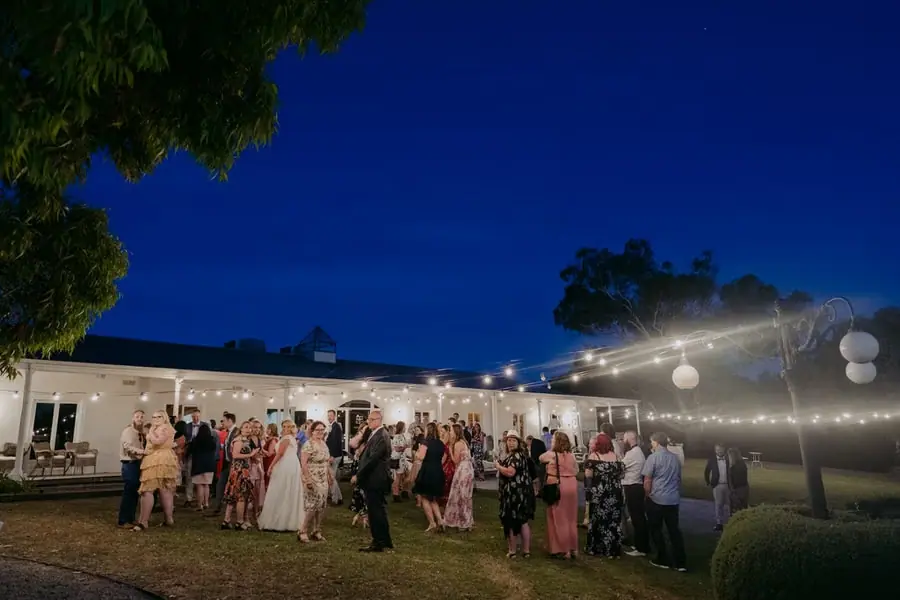Wide view of guests dancing outside the venue beneath a deep blue evening sky