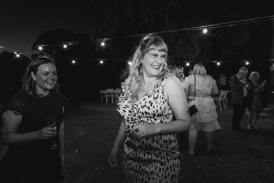 Black-and-white photograph of women dancing beneath garden lights