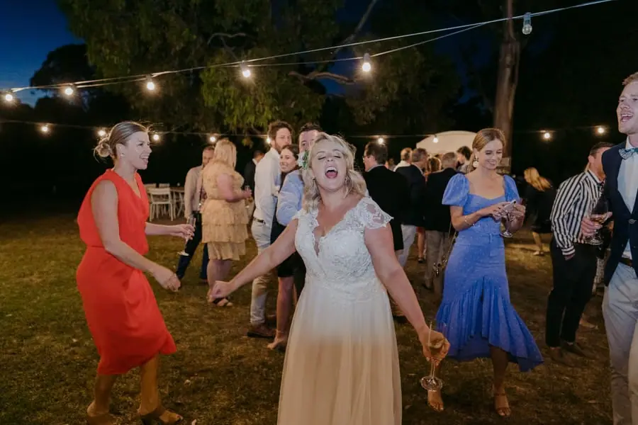 Bride laughing among dancing guests outdoors