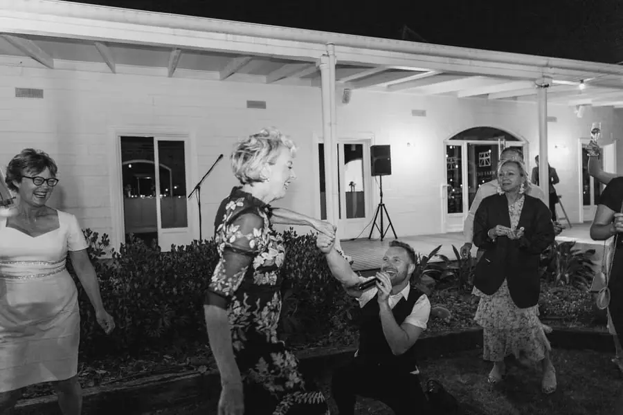 Black-and-white photograph of guests dancing beside the reception verandah