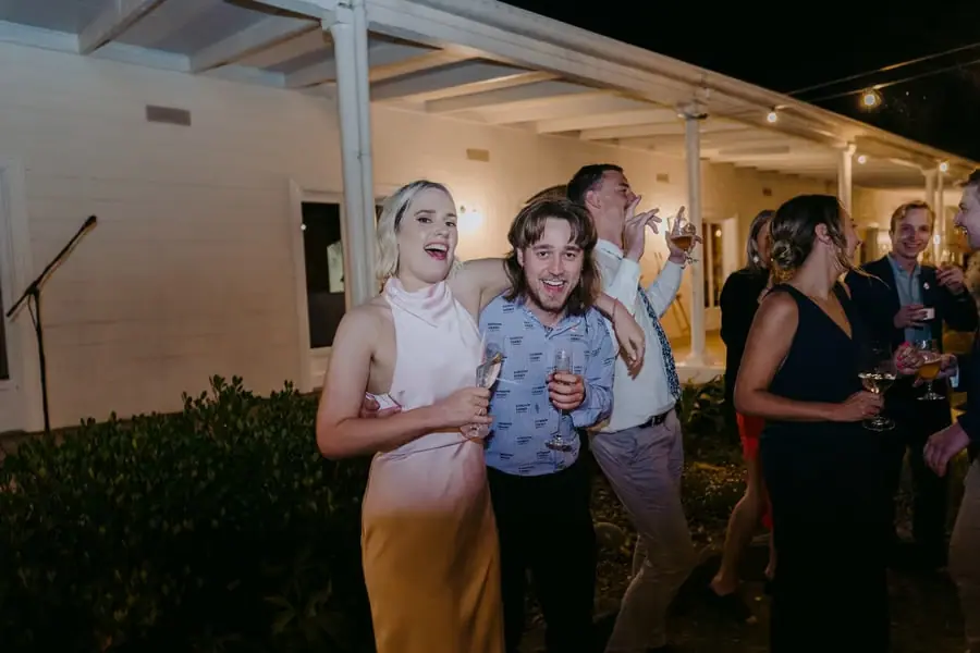 Guests smiling and holding drinks while posing closely together
