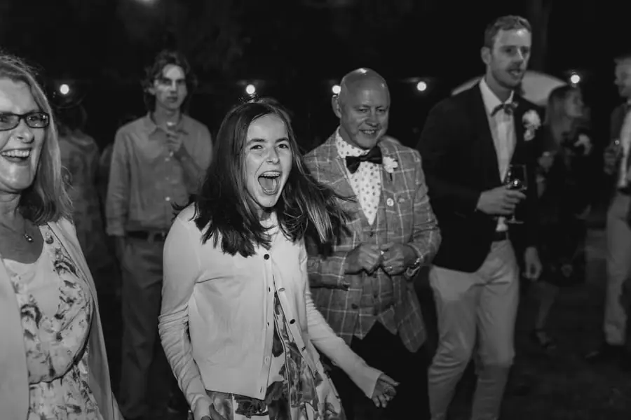 Black-and-white photograph of guests singing and laughing on the dance floor