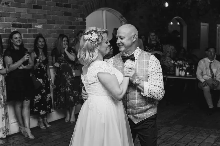 Black-and-white photograph of the bride dancing with a man in a checked waistcoat