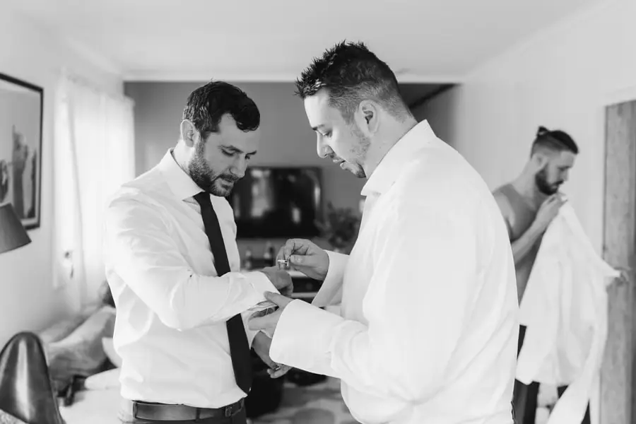 Black and white photograph of two men fastening their shirt cuffs