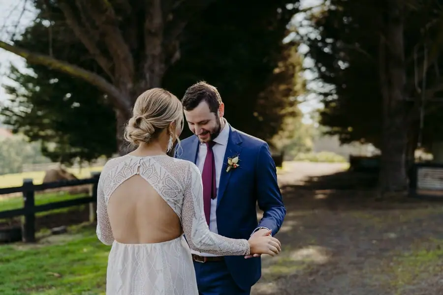 Groom looking down at the bride's dress while they hold hands