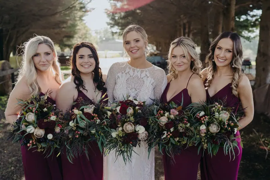 Bride and four bridesmaids posing with dark red and pale bouquets