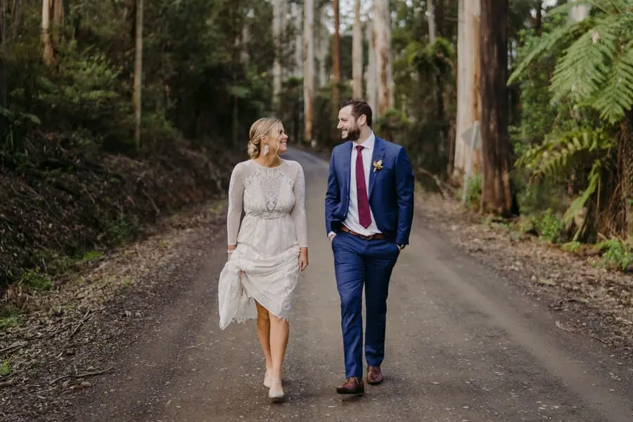 Bride and groom walking together along a forest road