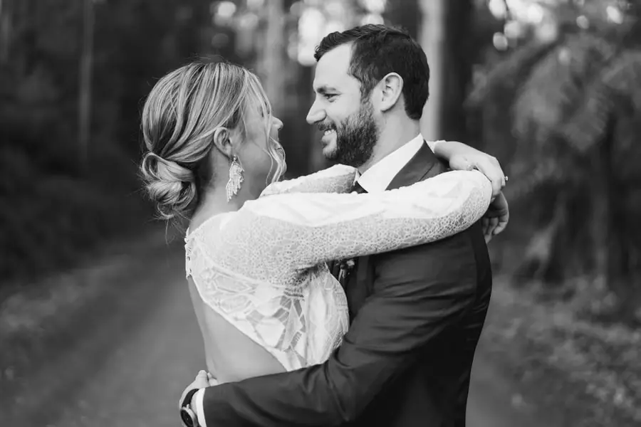 Black and white photograph of the couple smiling with her arms around his neck