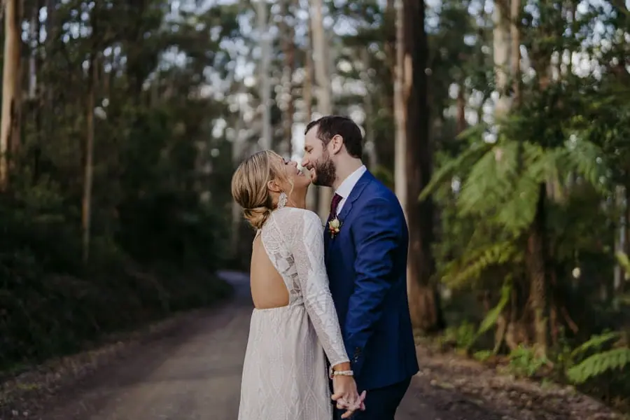 Bride and groom kissing beneath tall forest trees