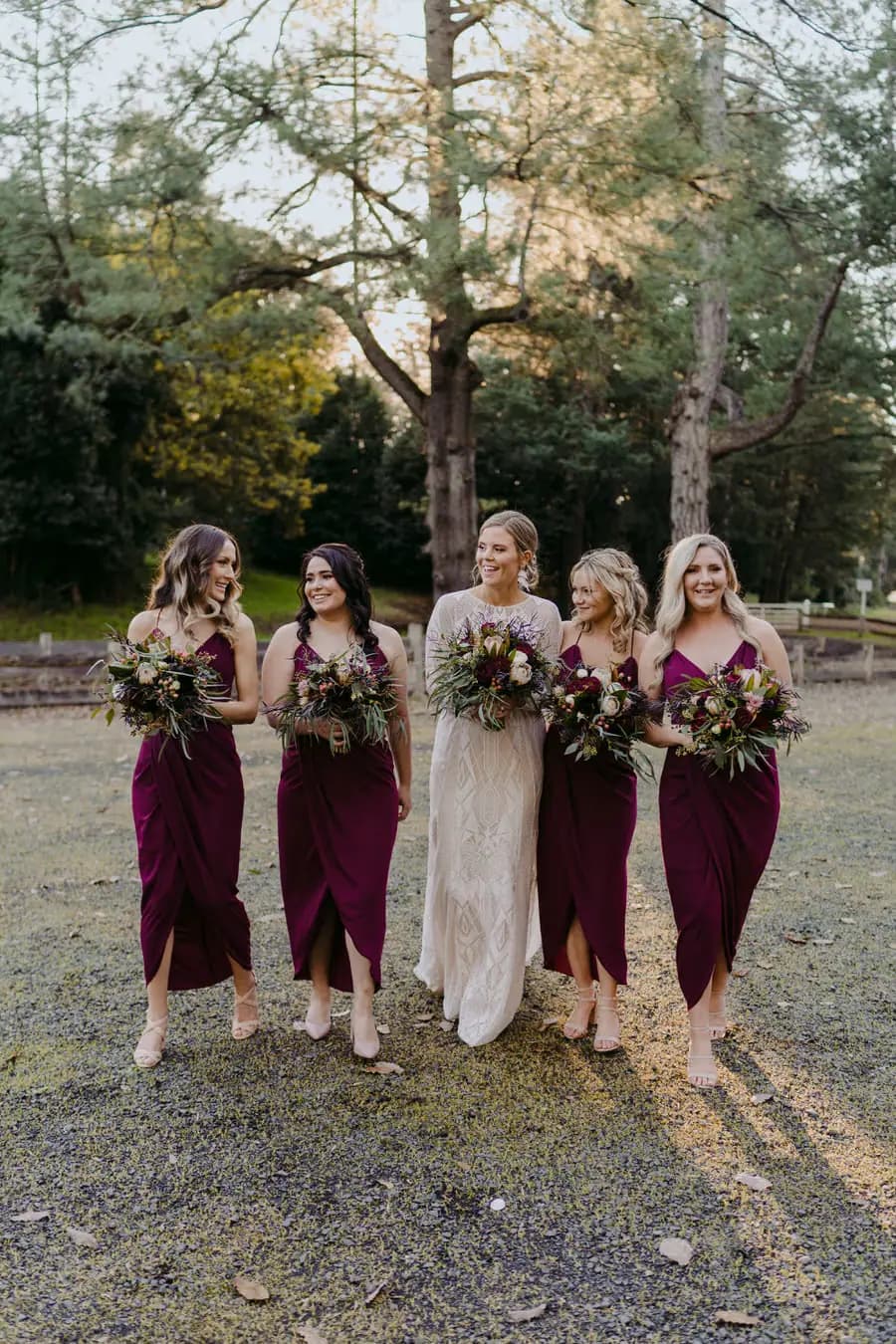 Bride and bridesmaids posing together with bouquets beside railway tracks