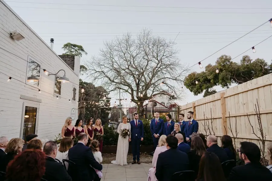 Wide view of the wedding party and seated guests during the courtyard ceremony