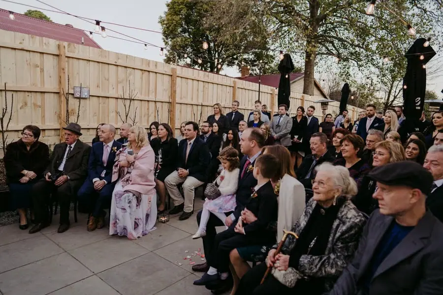 Seated guests smiling while watching the courtyard ceremony
