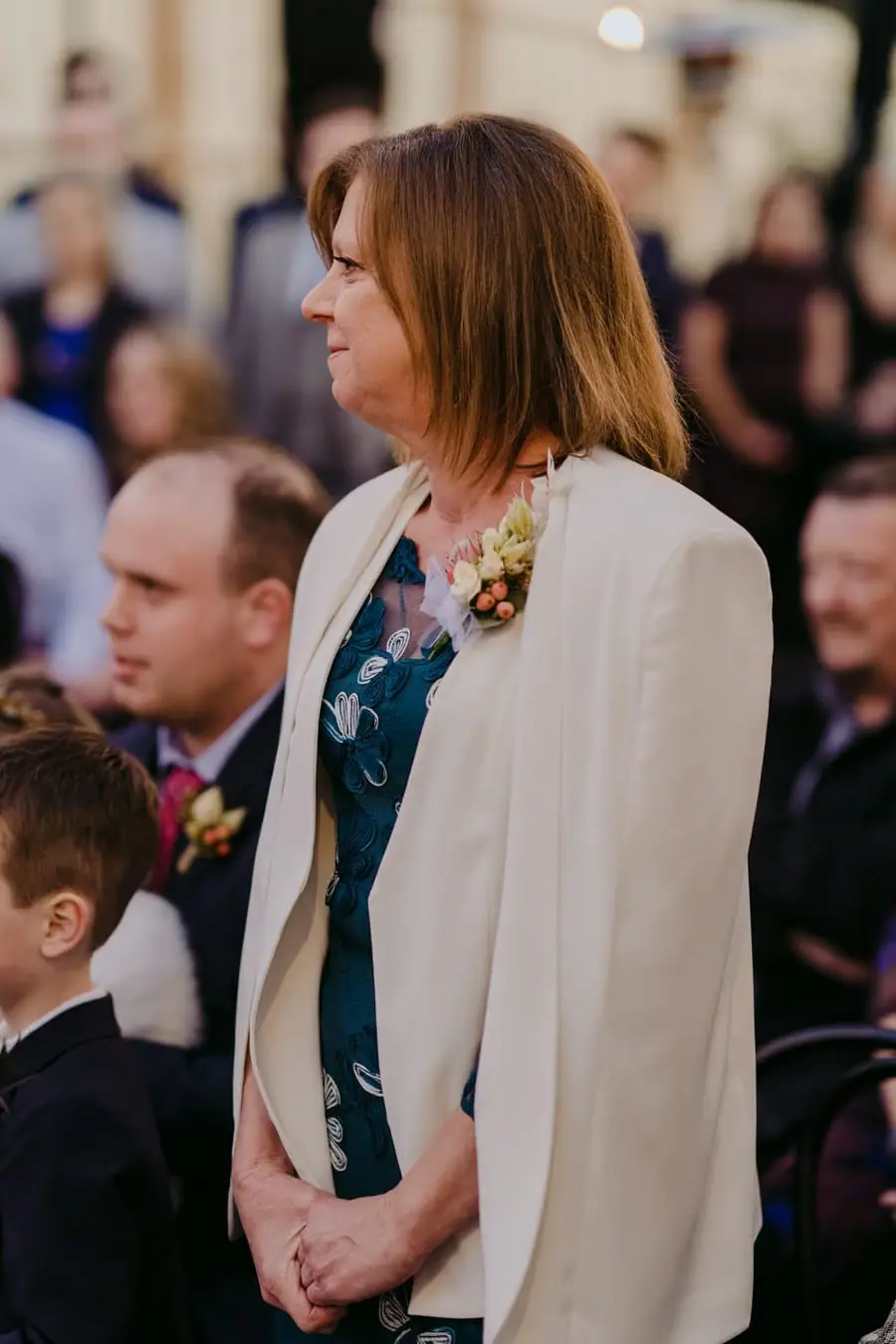 Woman standing among seated wedding guests during the ceremony