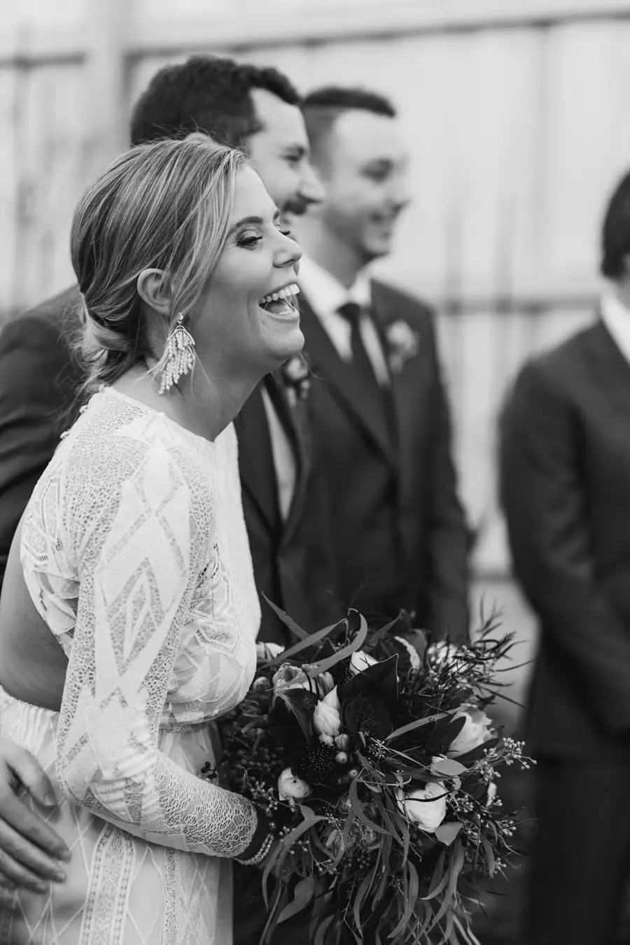 Black and white photograph of the smiling bride standing beside the groom