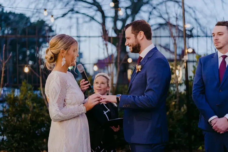 Bride speaking into a microphone while holding the groom's hand
